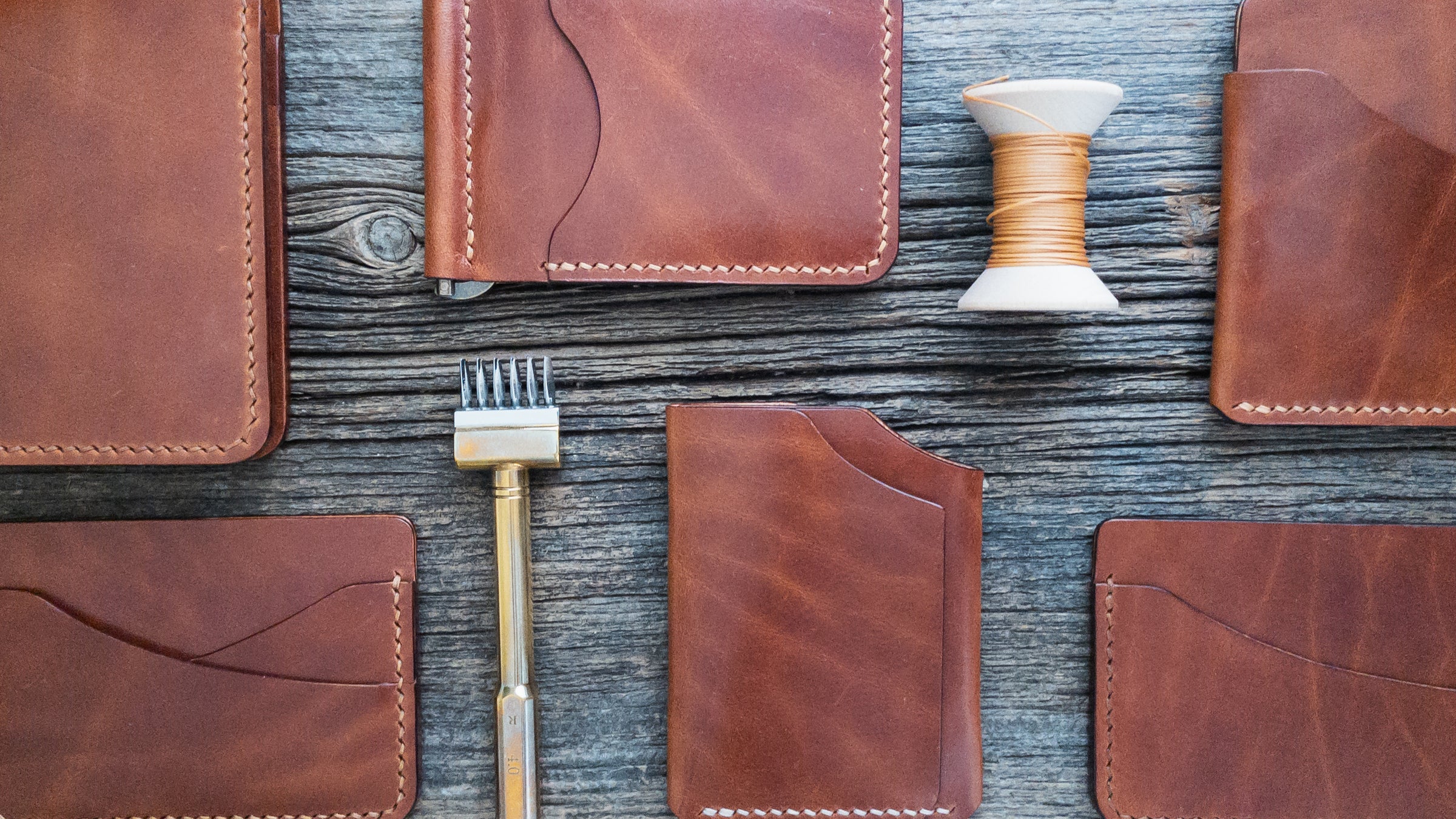 Group of various wallets and card holders in Buck Brown leather laid out on a weathered barn board