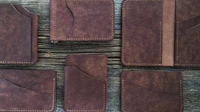 Group of various wallets and card holders in Tobacco Pueblo leather laid out on a weather barn board