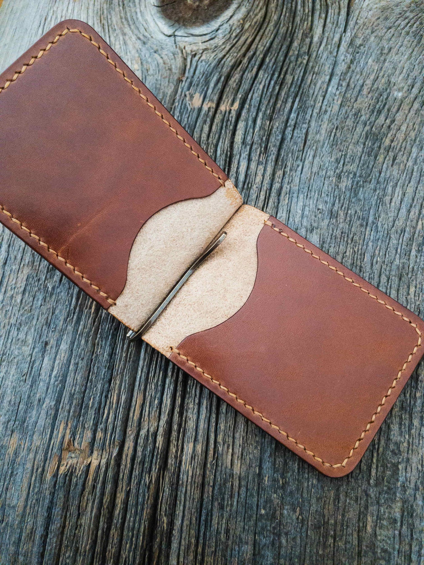 Folding Clip Wallet in Buck Brown full grain traditional harness leather, hand stitched with Ritza Tiger thread in Tan. Sitting open showing  brass spring clip and inner pockets