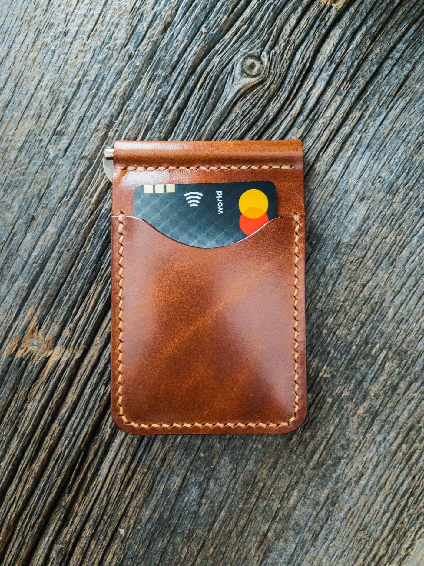 Folding wallet in buck brown full grain traditional harness leather, hand stitched pockets with Ritza Tiger thread in Tan, and brass spring clip. Credit car in outer pocket.